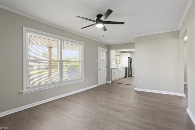 unfurnished living room with crown molding, baseboards, a ceiling fan, and wood finished floors