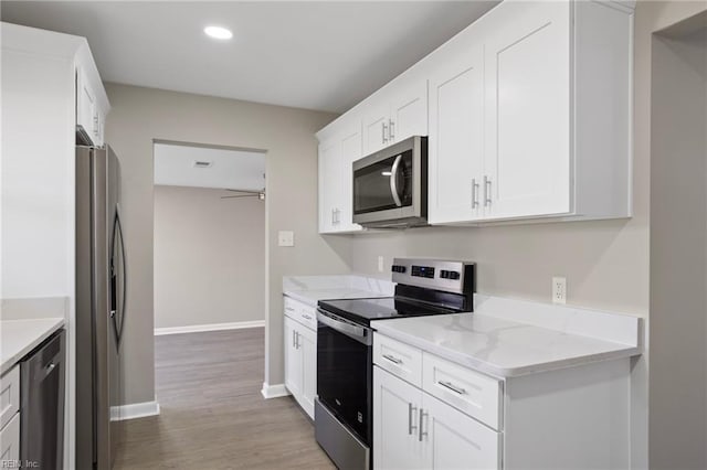 kitchen with appliances with stainless steel finishes, white cabinets, and ceiling fan