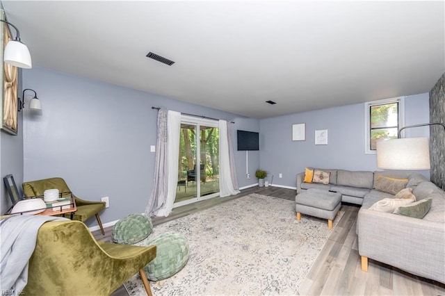 living area featuring baseboards, wood finished floors, and visible vents
