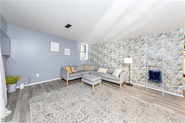 living area with wood finished floors, an accent wall, a fireplace, baseboards, and wallpapered walls