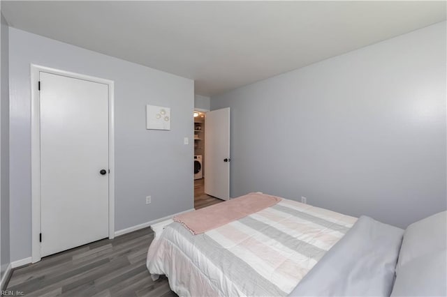 bedroom with washer / dryer, baseboards, and wood finished floors