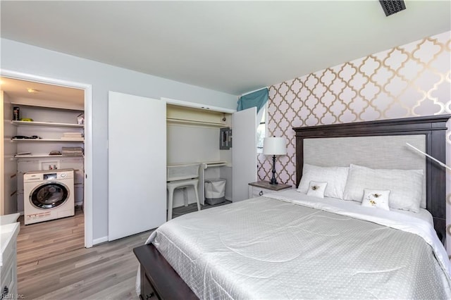 bedroom featuring a closet, visible vents, washer / dryer, wood finished floors, and a walk in closet