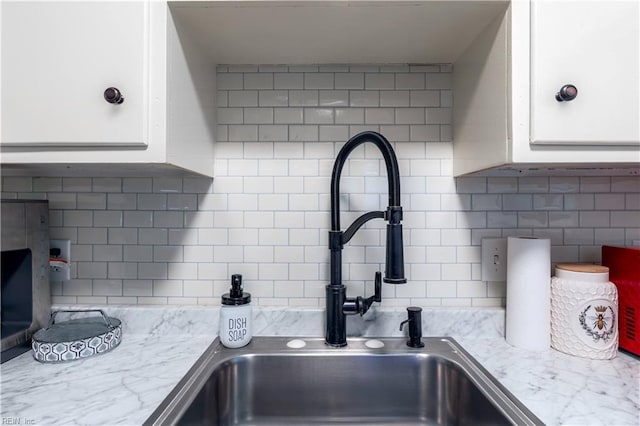 kitchen with a sink, decorative backsplash, and white cabinetry