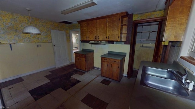 1233 Transylvania Ave, Chesapeake, VA 23324 - kitchen featuring wallpapered walls, brown cabinetry, a wainscoted wall, a sink, and hanging light fixtures