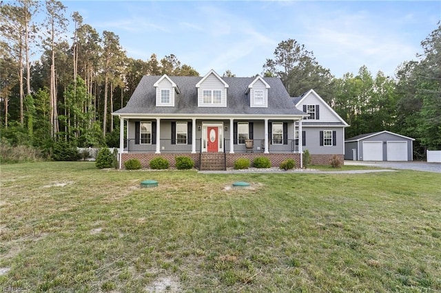 new england style home featuring a porch, an outbuilding, a front yard, and a garage