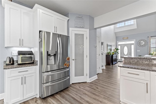 kitchen with white cabinetry, baseboards, stainless steel fridge with ice dispenser, and light wood-style floors