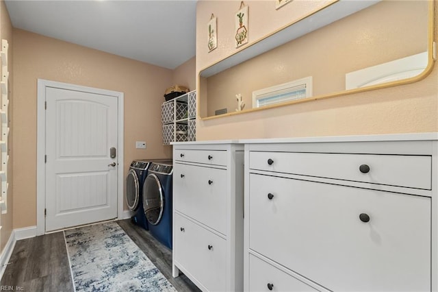 washroom with baseboards, dark wood finished floors, cabinet space, and washing machine and clothes dryer