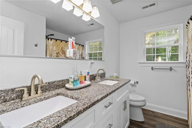 full bath with visible vents, a sink, wood finished floors, and a skylight