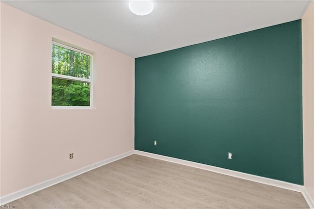 spare room featuring baseboards and light wood-style flooring
