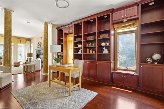office area featuring visible vents, ornamental molding, decorative columns, a glass covered fireplace, and dark wood-type flooring