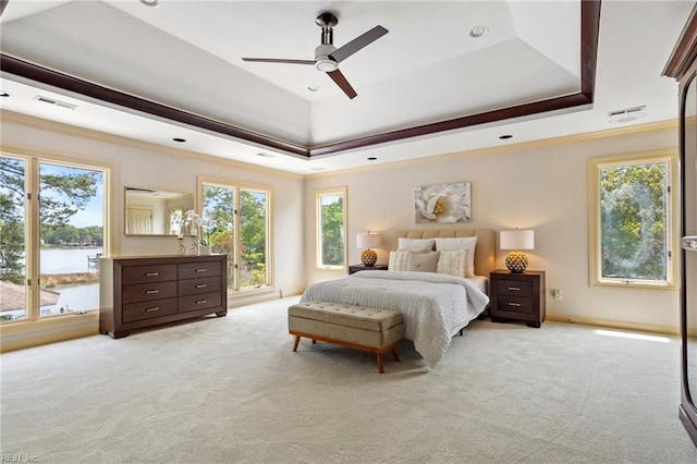 bedroom with light colored carpet, crown molding, a tray ceiling, and visible vents