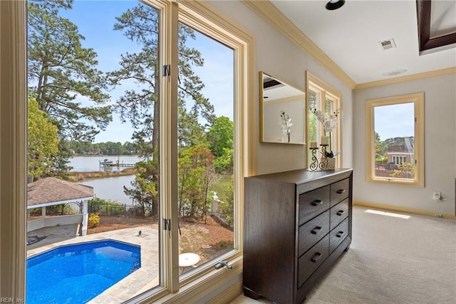 entryway featuring crown molding, a water view, light colored carpet, and visible vents