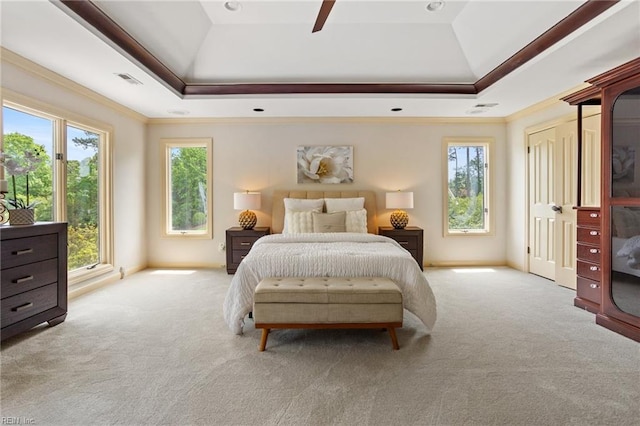 carpeted bedroom with crown molding, a tray ceiling, and visible vents