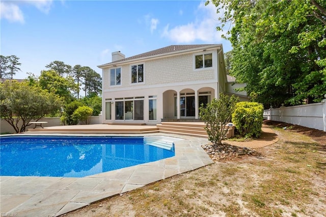 back of house featuring an outdoor pool, a patio area, a chimney, and fence