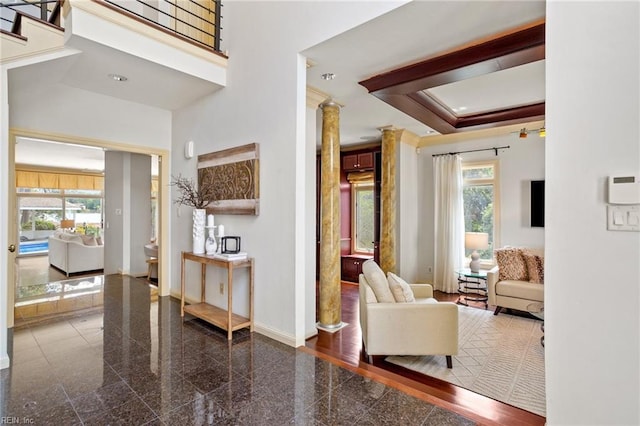 interior space featuring baseboards, decorative columns, a wealth of natural light, and granite finish floor