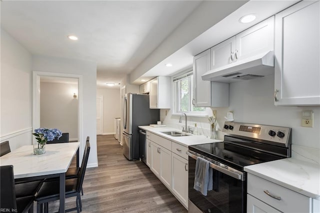 kitchen featuring wood finished floors, white cabinetry, under cabinet range hood, a sink, and appliances with stainless steel finishes