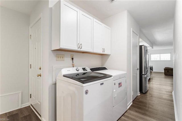 washroom featuring baseboards, washing machine and dryer, cabinet space, and wood finished floors