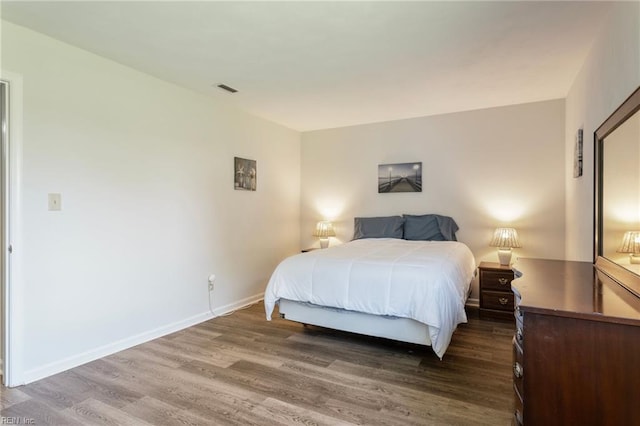 bedroom featuring baseboards, wood finished floors, and visible vents