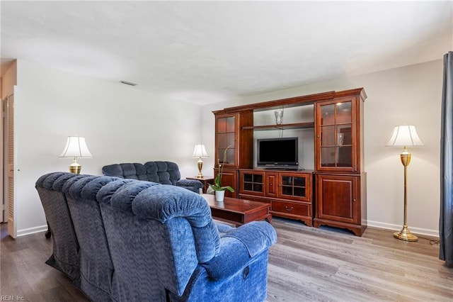 living area featuring baseboards, wood finished floors, and visible vents