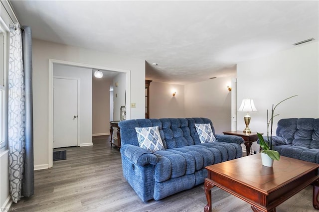 living room featuring baseboards, wood finished floors, and visible vents