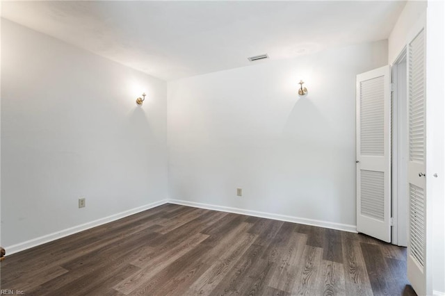unfurnished bedroom with visible vents, dark wood-style flooring, and baseboards