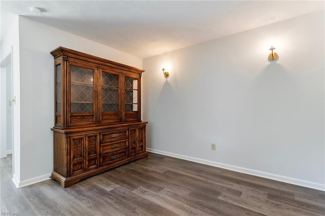 empty room featuring baseboards and dark wood-style floors