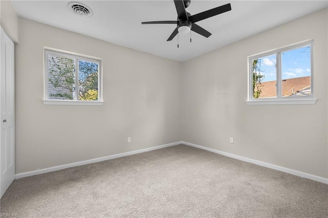 carpeted empty room featuring baseboards, plenty of natural light, a ceiling fan, and visible vents