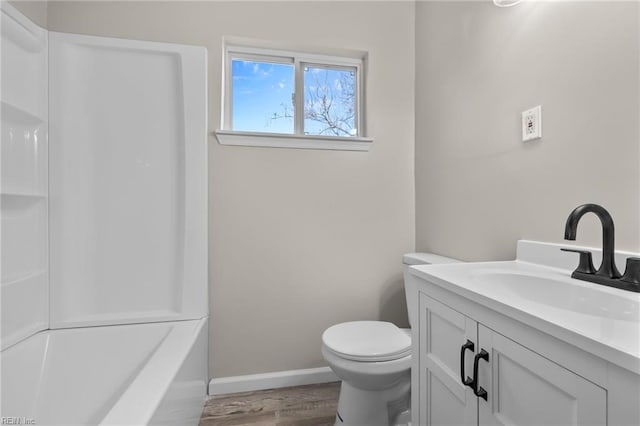 bathroom with baseboards, wood finished floors, toilet, and vanity