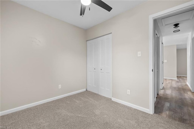 unfurnished bedroom featuring carpet floors, baseboards, attic access, and a closet
