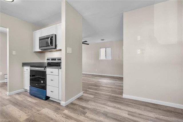 kitchen featuring baseboards, light wood finished floors, and appliances with stainless steel finishes