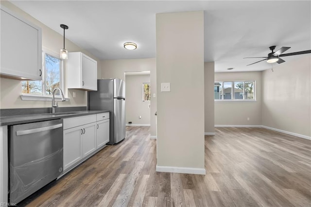 kitchen with dark countertops, appliances with stainless steel finishes, ceiling fan, a sink, and white cabinetry
