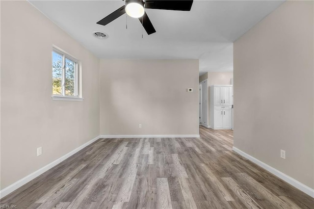 unfurnished room featuring ceiling fan, baseboards, visible vents, and light wood-style flooring