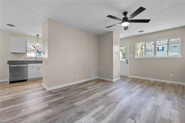 unfurnished living room with baseboards, a ceiling fan, light wood finished floors, and visible vents