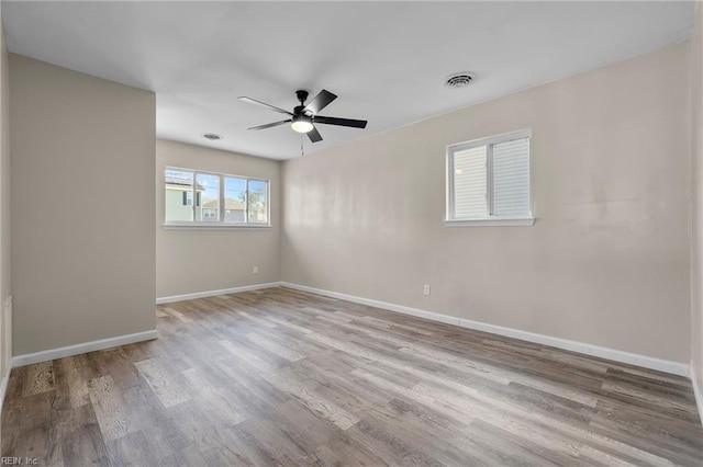 unfurnished room with visible vents, baseboards, ceiling fan, and wood finished floors