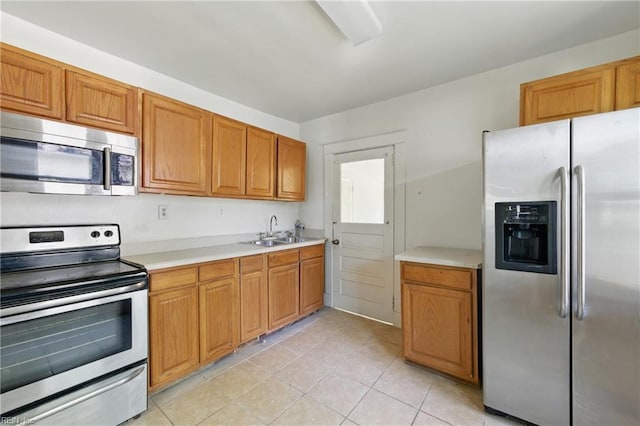 kitchen with brown cabinetry, light countertops, a sink, light tile patterned floors, and stainless steel appliances