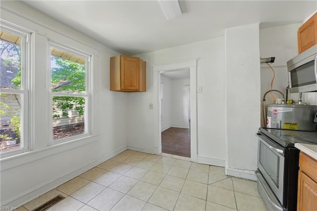 kitchen with visible vents, light tile patterned floors, electric water heater, and stainless steel appliances