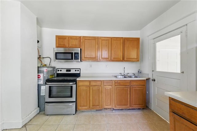 kitchen featuring light countertops, appliances with stainless steel finishes, a sink, and electric water heater