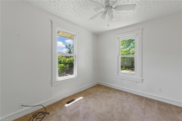 carpeted spare room with visible vents, a ceiling fan, a textured ceiling, and a healthy amount of sunlight