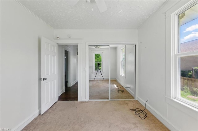 unfurnished bedroom with ornamental molding, carpet flooring, a textured ceiling, and multiple windows