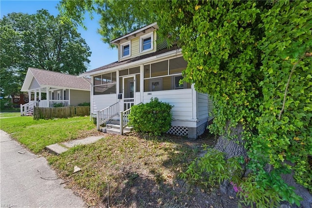 bungalow-style home with a sunroom and a front lawn