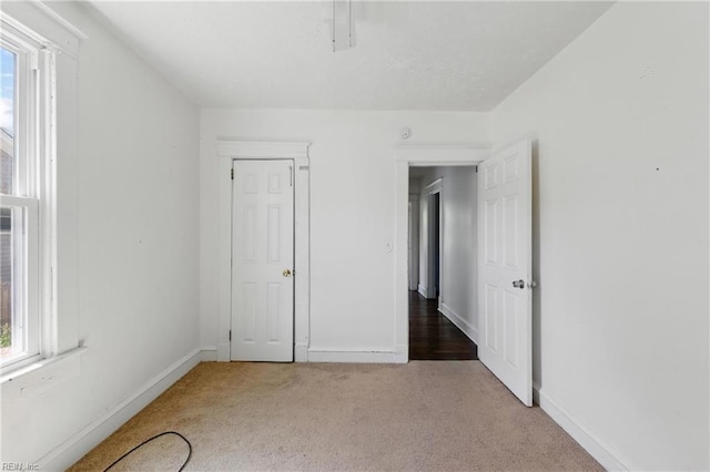 unfurnished bedroom with baseboards, multiple windows, and carpet flooring