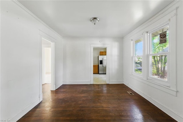 unfurnished room with baseboards, visible vents, ornamental molding, and hardwood / wood-style floors