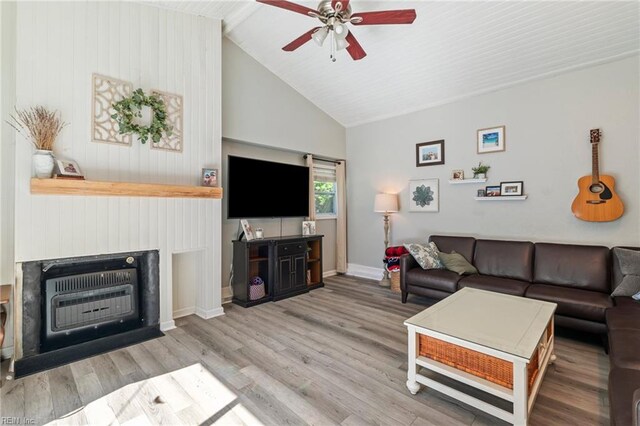 living room featuring a ceiling fan, heating unit, baseboards, high vaulted ceiling, and wood finished floors