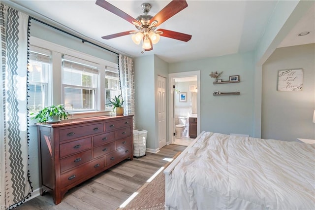 bedroom featuring light wood finished floors, connected bathroom, baseboards, and a ceiling fan