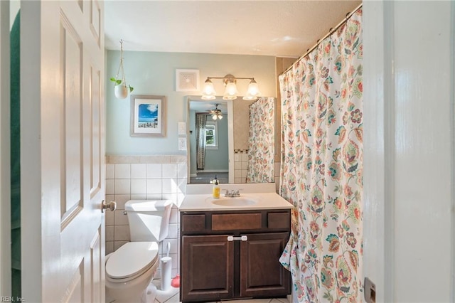 bathroom featuring toilet, tile walls, vanity, and a ceiling fan