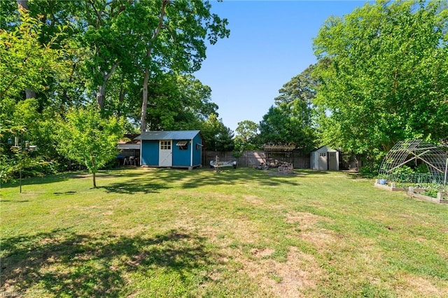 view of yard with an outdoor structure, a shed, a vegetable garden, and a fenced backyard