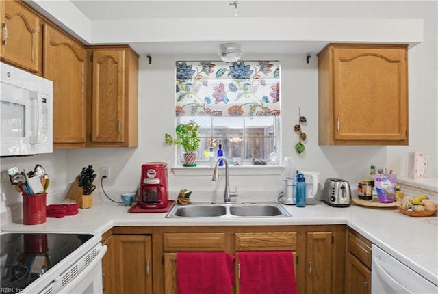 kitchen with a sink, light countertops, brown cabinets, and white appliances