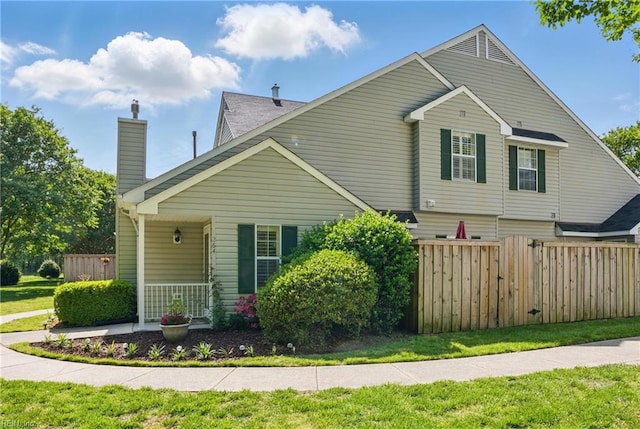 view of property exterior with fence, a chimney, a yard, and a porch