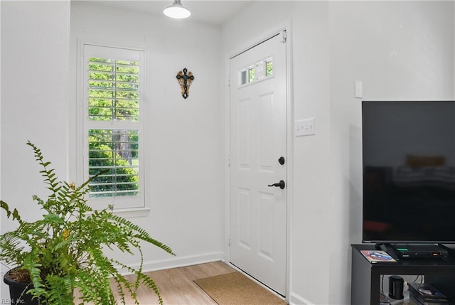 entryway with light wood-style floors, baseboards, and plenty of natural light