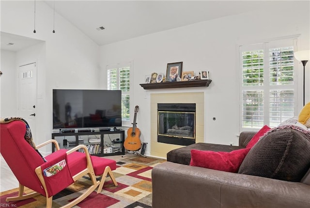 living room featuring visible vents, a glass covered fireplace, and vaulted ceiling